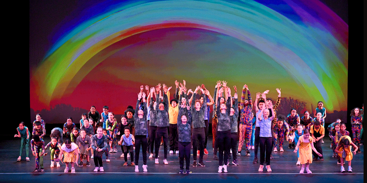Kids dancing on stage with arms up or bent near the ground