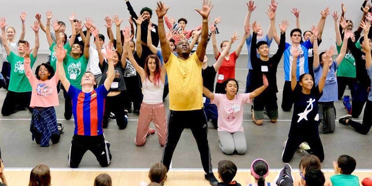 Teacher and students with arms raised