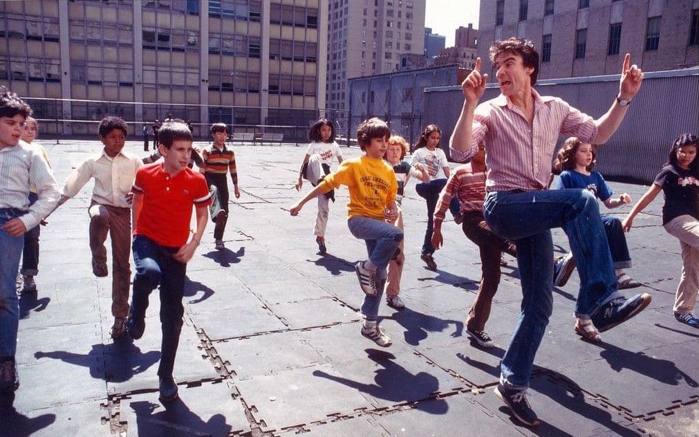 Kids dancing in a playground following an NDI instructor